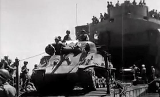 Zwart-wit beeld van een Sherman tank met Nederlandse militairen wordt vanuit het schip aan wal gereden ten tijden de eerste 'politionele actie'