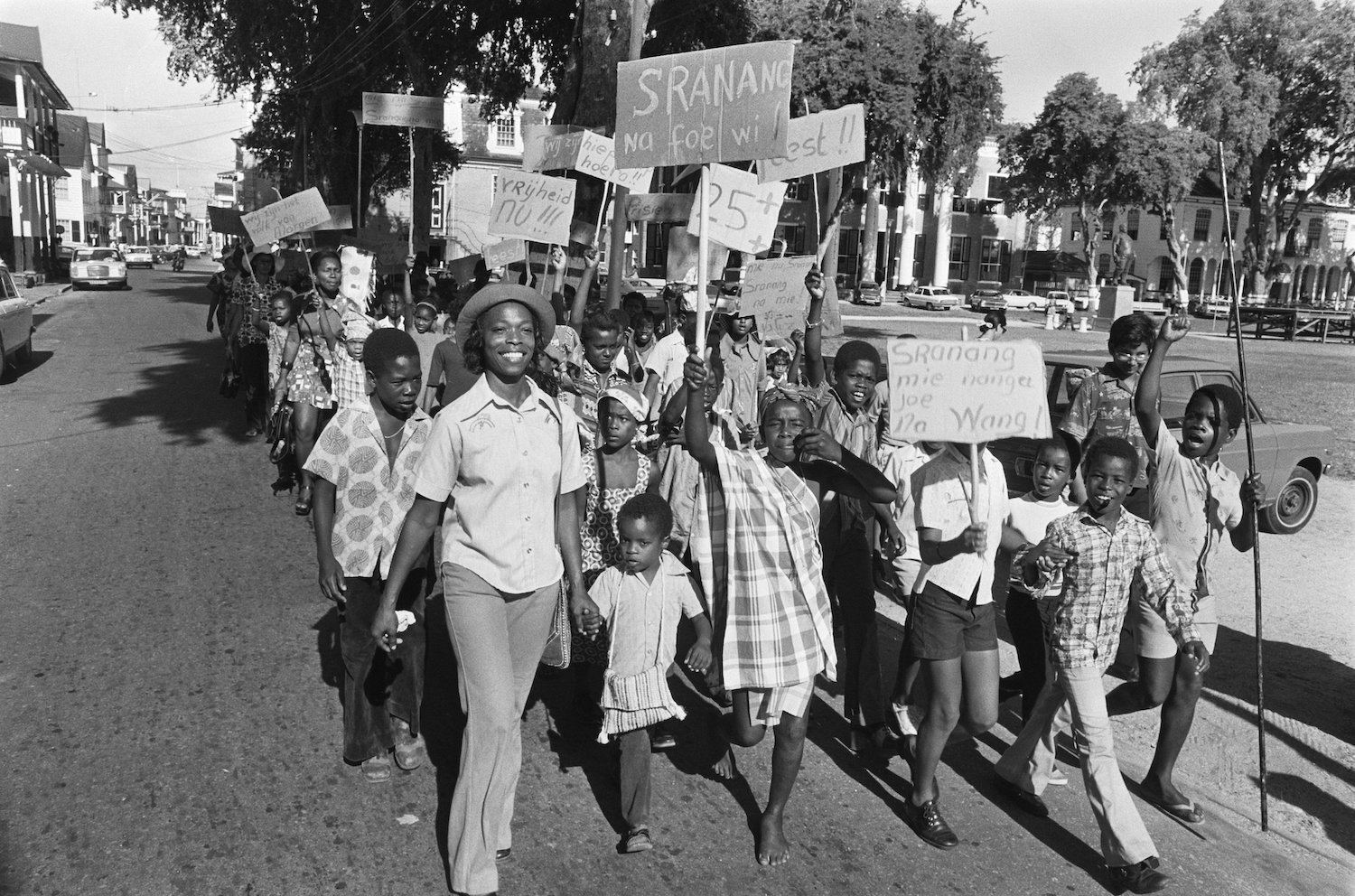Demonstratie op straat van Surinamers met borden waarop leuzen staan
