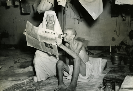 Foto van een verpleegster en oud-kampgevangene lezen de Oranje in het Mater dela Rosa Hospitaal in Batavia