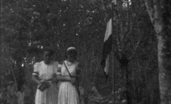 Still met twee vrouwen naast de Nederlandse vlag in het vrouwenkamp Aek Paminke