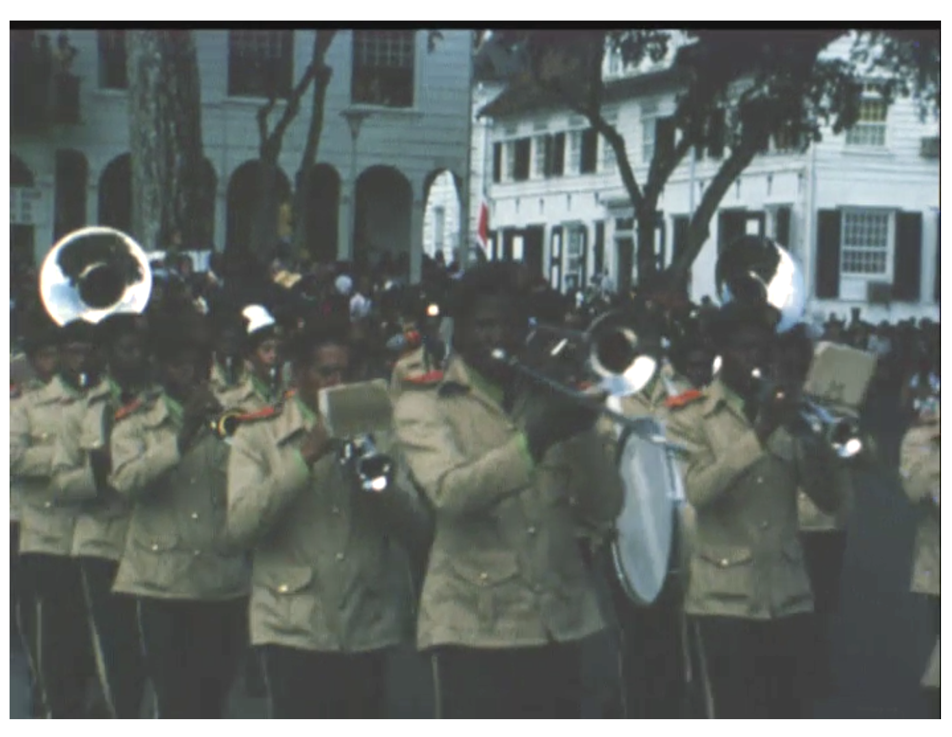 Foto van het gloednieuwe Surinaamse militaire muziekkorps dat door de straten van Paramaribo paradeert